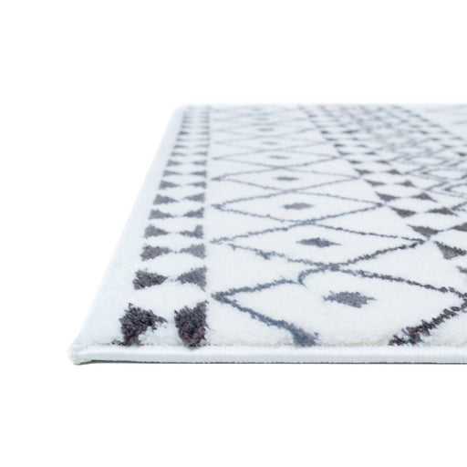 A corner of a black and white area rug with geometric designs.