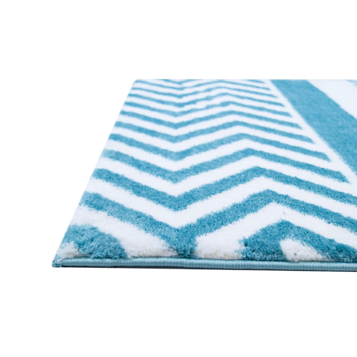 A corner of a blue and white area rug with geometric designs.