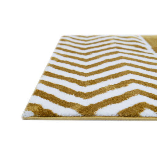 A corner of a yellow and white area rug with geometric designs.