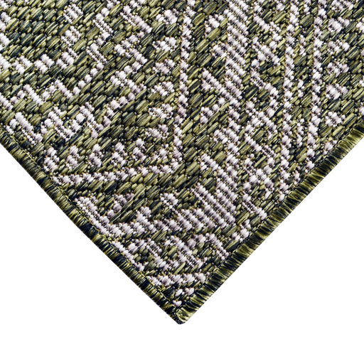 A corner of a green flat weave outdoor runner rug with geometric designs.