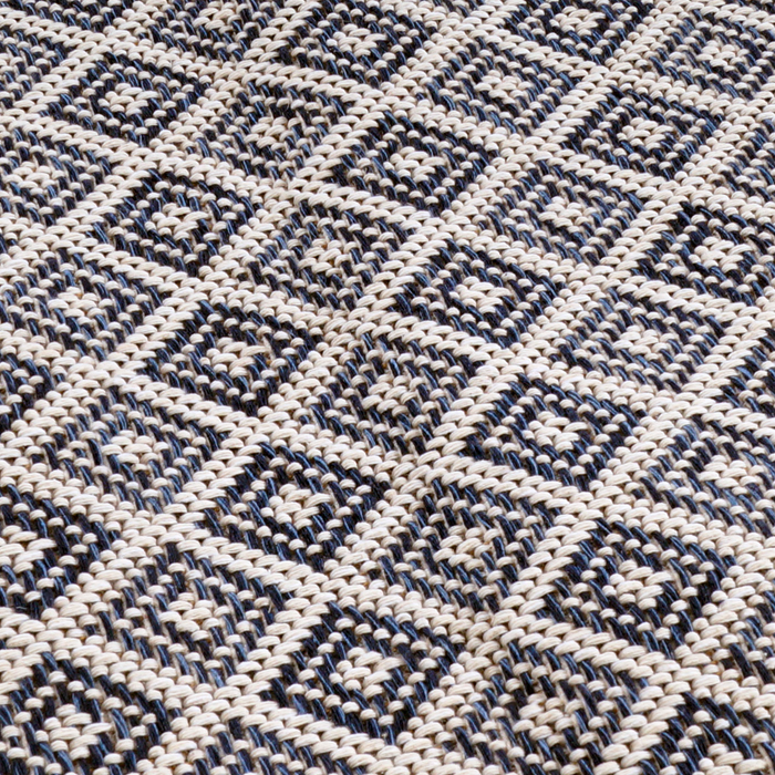 A detail of a blue flat weave area rug with geometric diamond designs.