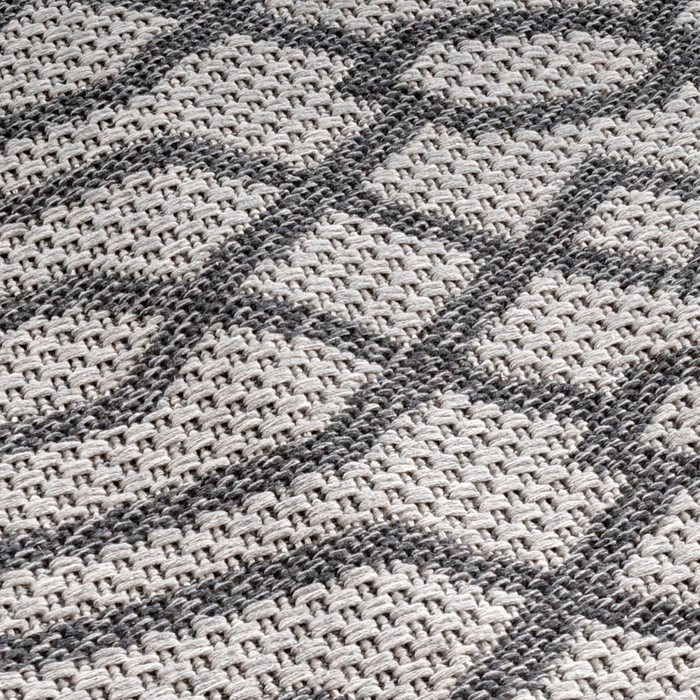 A detail of a grey flat weave area rug with modern geometric designs.