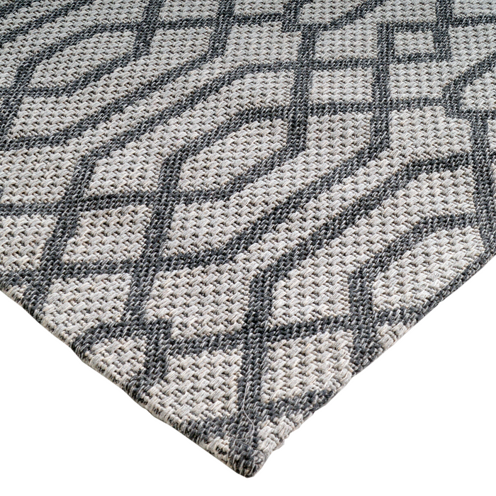 A corner of a grey flat weave area rug with modern geometric designs.