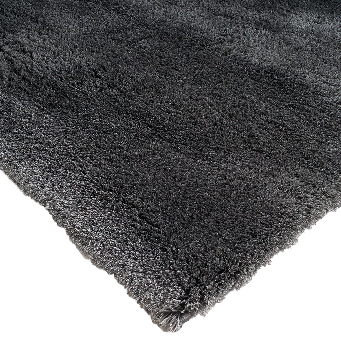 A corner of a solid grey shag area rug.