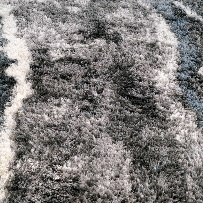 A detail of a grey textured area rug with a marbled design.