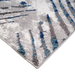 A corner of a grey and blue area rug with distressed abstract designs.