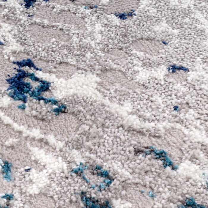 A detail of a grey and blue area rug with distressed abstract designs.