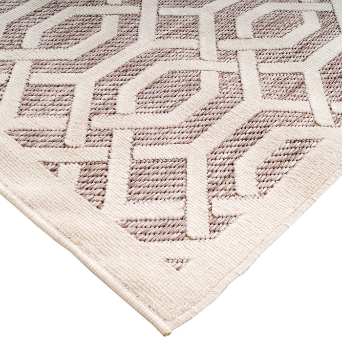 A corner of a beige area rug with geometric designs.