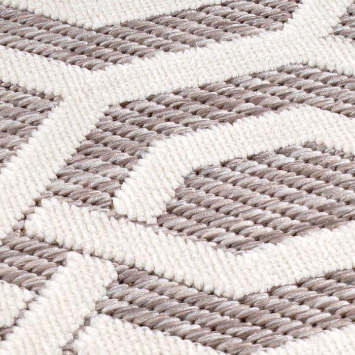 A detail of a beige area rug with geometric designs.