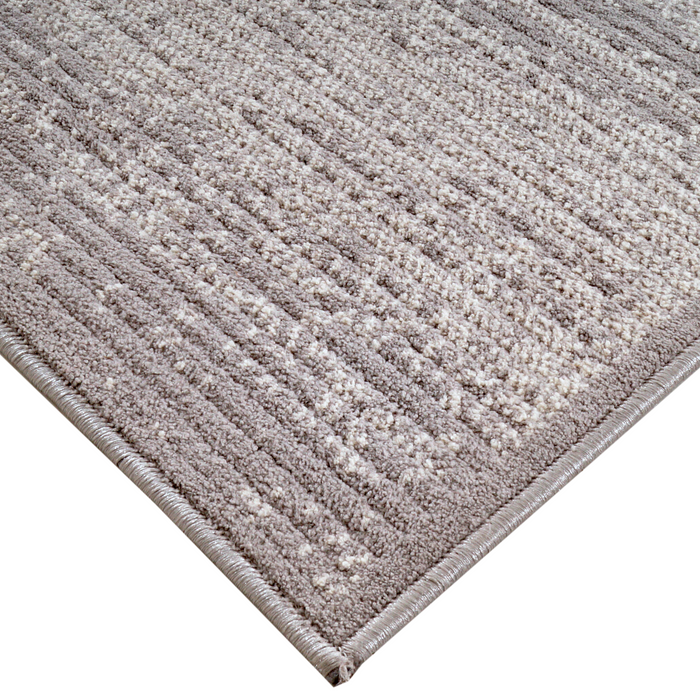 A corner of a grey textured area rug with embossed striped designs.