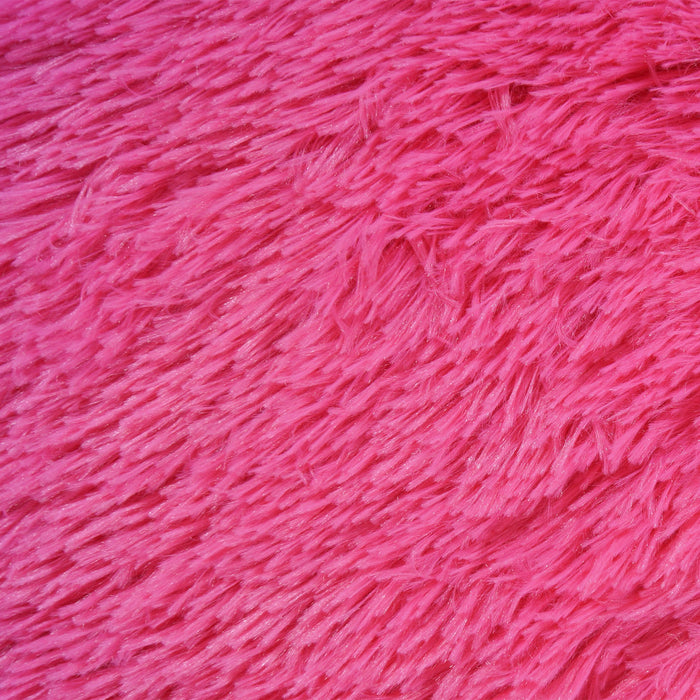 A detail of a solid fuchsia shag area rug.