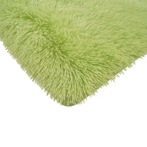 A corner of a solid lime shag area rug.